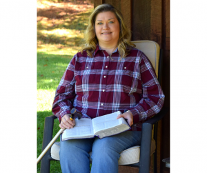 woman sitting in chair with Bible in lap and cane by her side