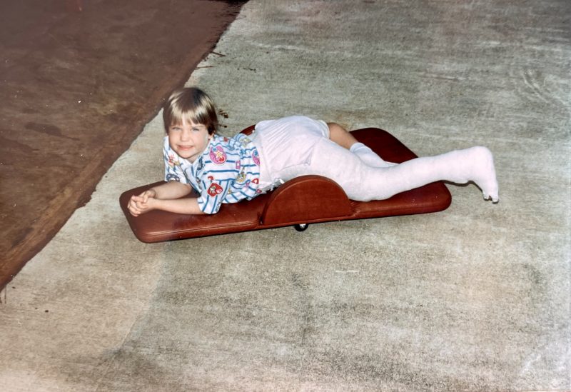 Cindy, age 7, lying on a brown board in full-length body cast